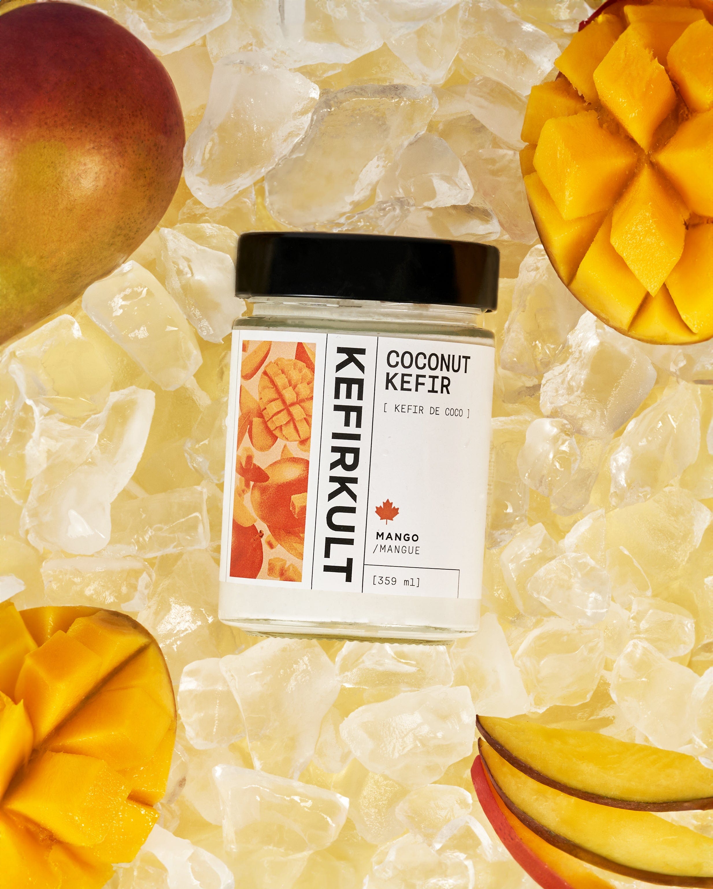 Jar labeled 'KEFIRKULT' 'COCONUT KEFIR' [ KEFIR DE COCO ] 'MANGO / MANGUE' [359 ml] on ice with mango slices
